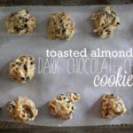 Overhead of Toasted Almond Dark Chocolate Chip Cookie dough on a parchment-lined baking sheet with text