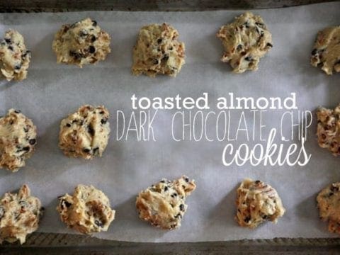 Overhead of Toasted Almond Dark Chocolate Chip Cookie dough on a parchment-lined baking sheet with text
