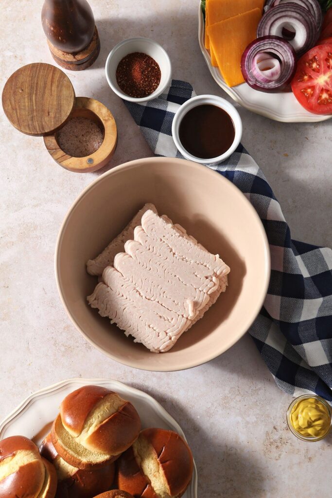 Ingredients to make baked turkey burgers in bowls with a blue buffalo check napkin