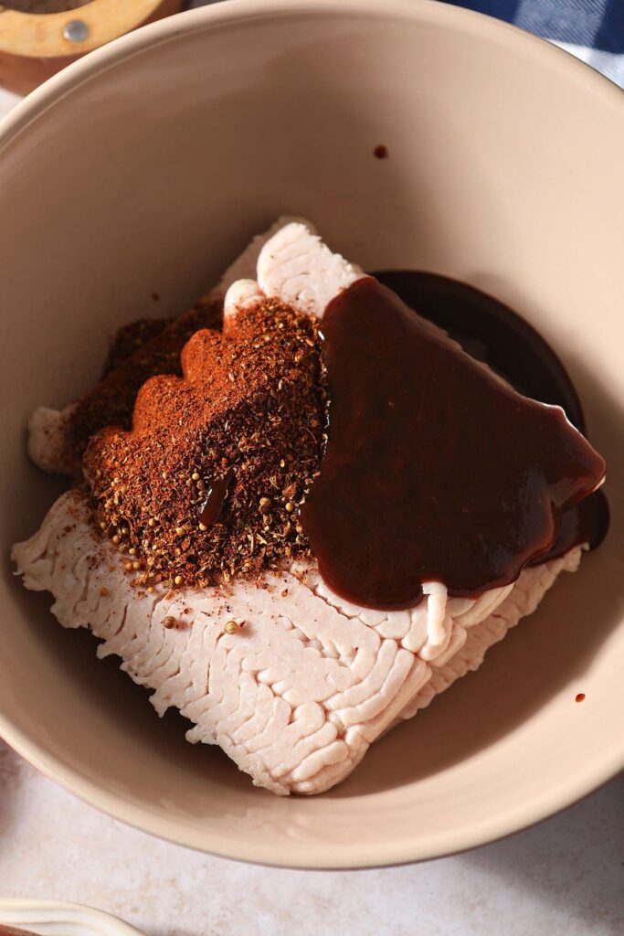 BBQ sauce and BBQ dry rub on top of ground turkey in a large bowl