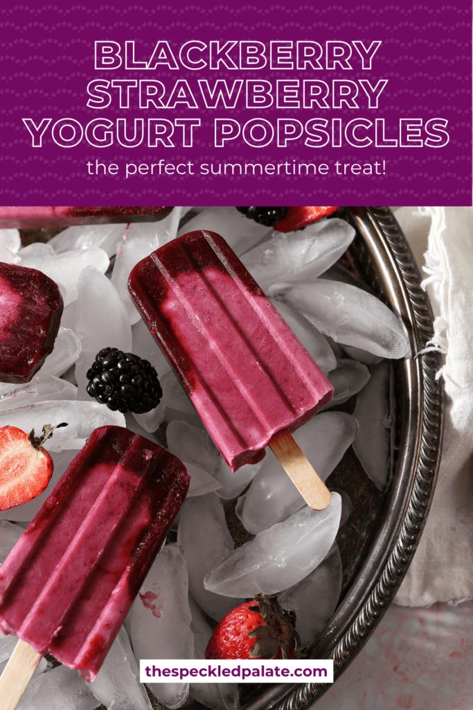 A tray of pink popsicles with berries on top of ice in a silver tray with the text blackberry strawberry yogurt popsicles the perfect summertime treat