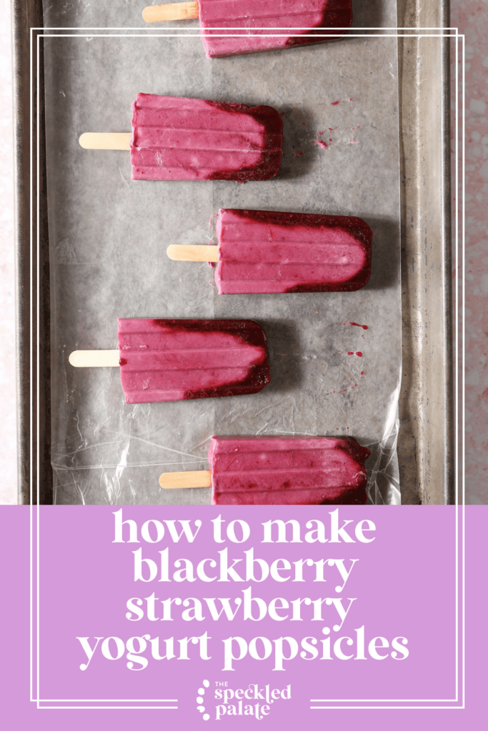 Five ombre pink popsicles on a wax paper-lined sheet pan with the text how to make blackberry strawberry yogurt popsicles