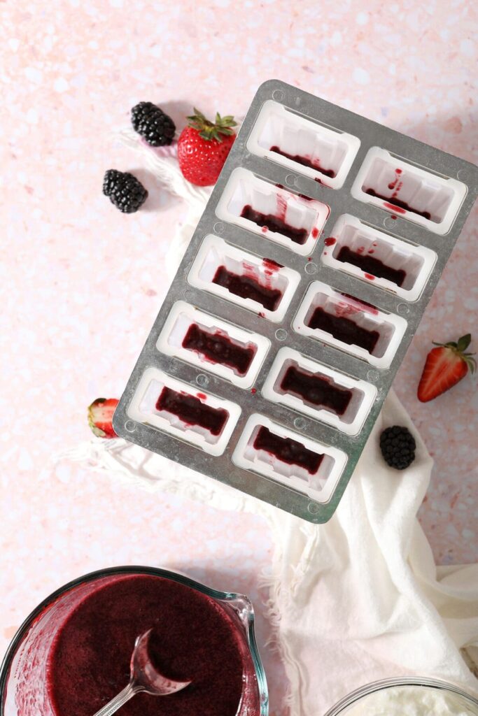 Strained berry puree is added to the bottom of popsicle molds