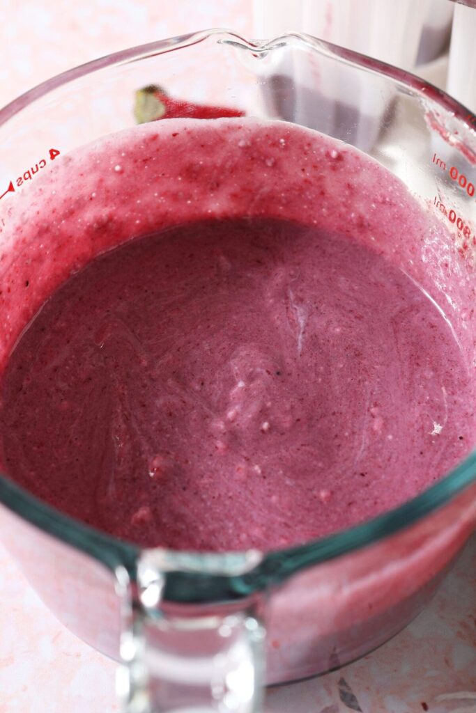 Berry yogurt popsicle mixture in a liquid measuring cup before going into molds