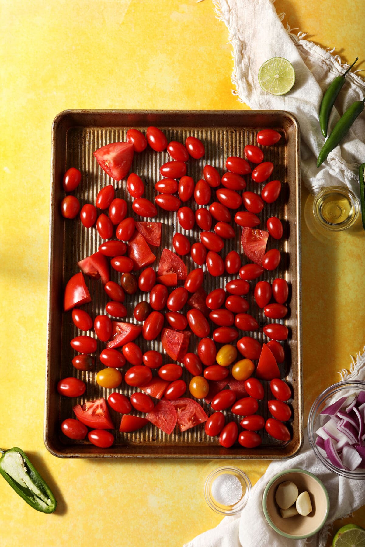 Tomatoes and peppers in a roasting pan on a yellow surface