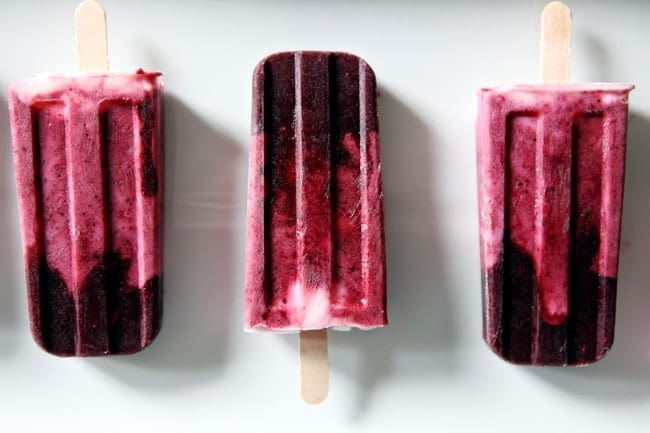 Three Blackberry and Strawberry Yogurt Popsicles on a white platter