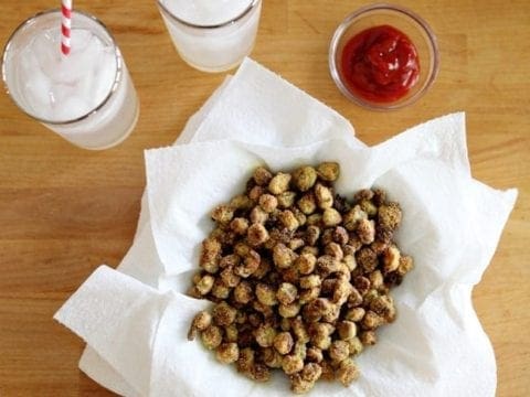Overhead of Oven Fried Okra on top of paper towels with a bowl of ketchup and two lemonades