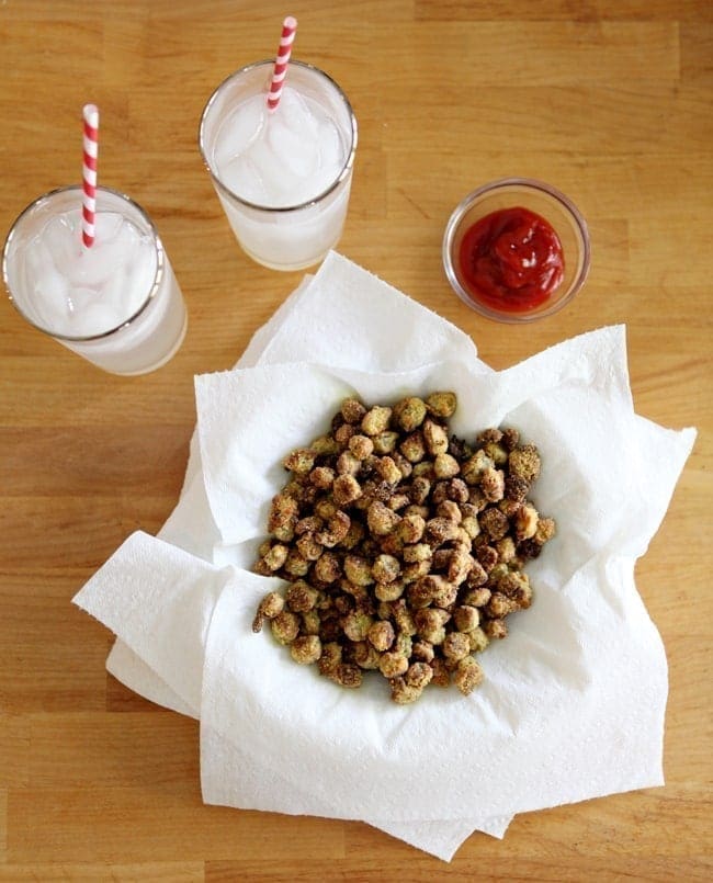 Overhead of Oven Fried Okra on top of paper towels with a bowl of ketchup and two lemonades