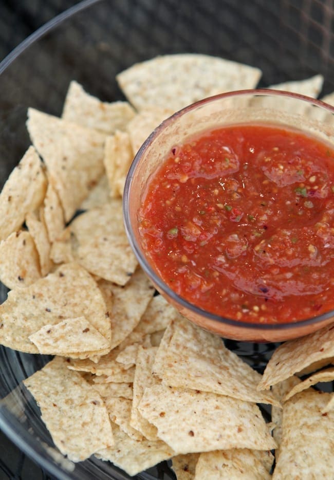 A close up of a bowl of roasted salsa surrounded by tortilla chips