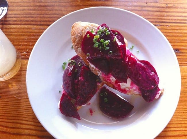 Bruschetta with goat cheese, beets and chives on a white plate