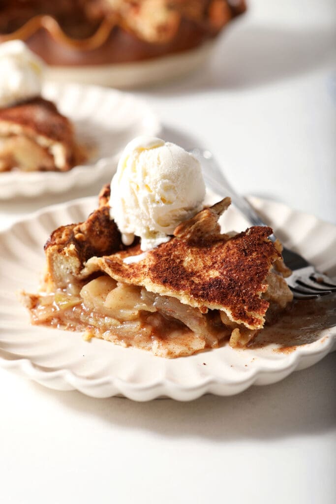 Close up of a slice of apple pie with a scoop of ice cream on top