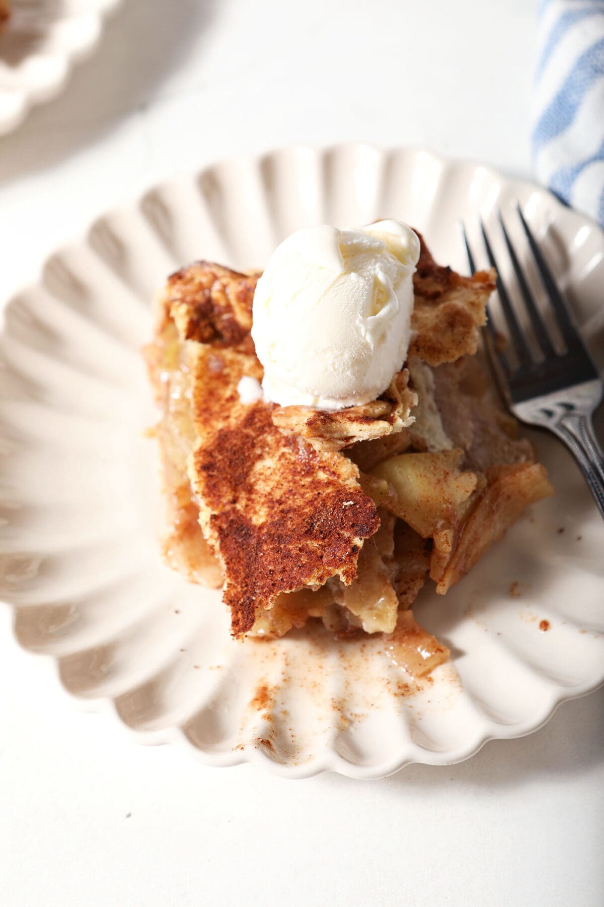 Overhead of a cinnamon apple pie slice topped with ice cream with a fork
