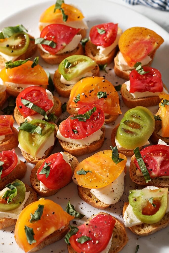 Heirloom Tomato Bruschetta garnished with fresh basil slices on a white platter