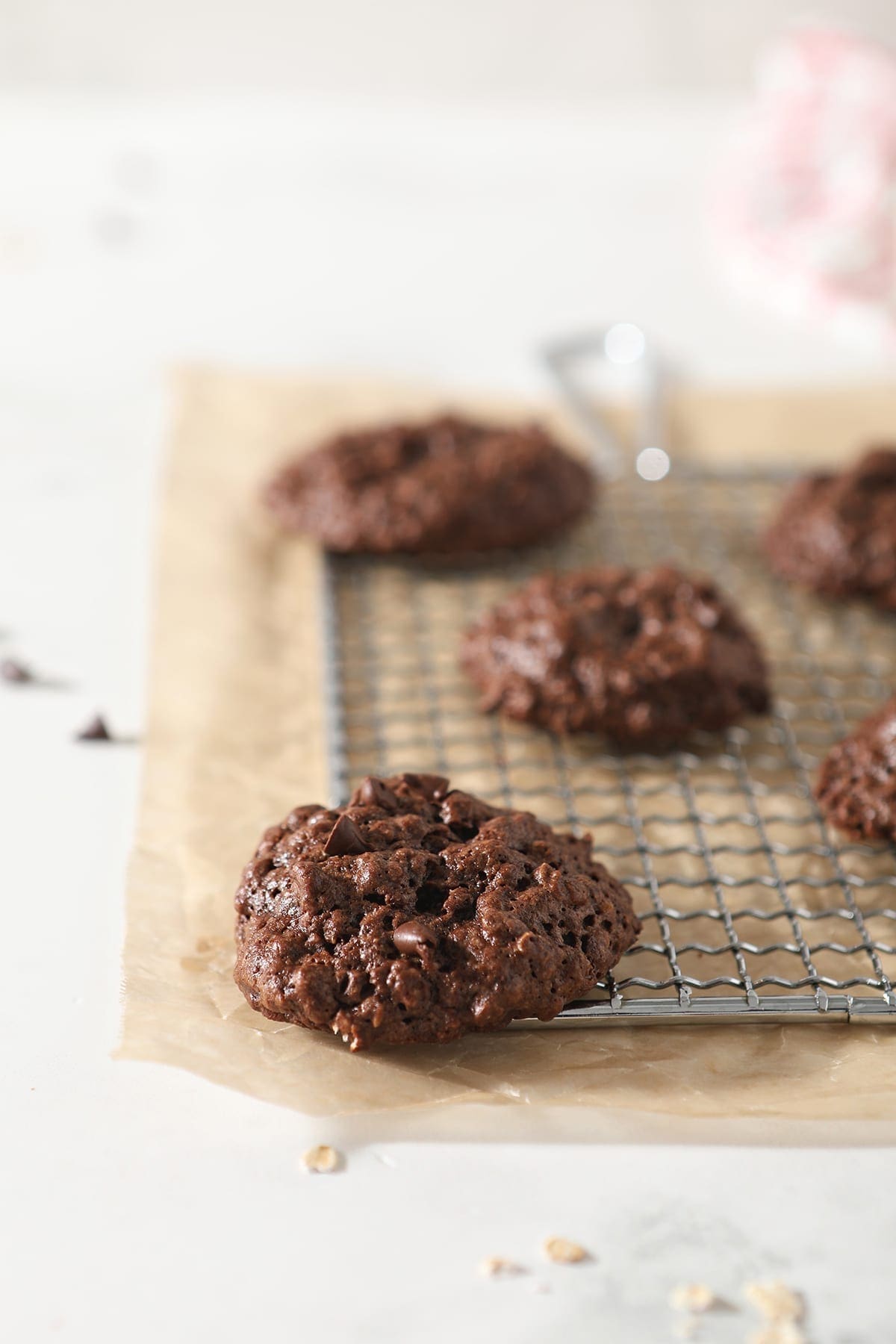  A few Gluten Free Chocolate Cookies sit on a metal grate on top of parchment paper