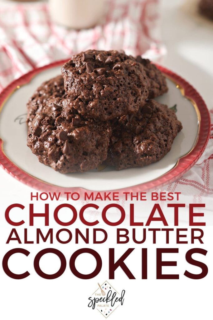 A stack of Chocolate Almond Butter Cookies with Chocolate Chips sit on a red-rimmed plate sitting on a red plaid towel with the text 'how to make the best chocolate almond butter cookies'