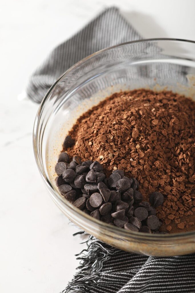 a glass mixing bowl with chocolate chips and cocoa powder