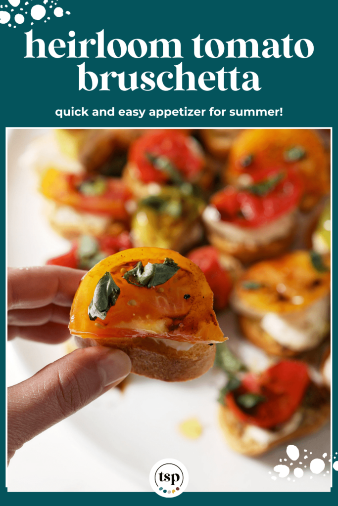 A hand holds a bruschetta with a yellow tomato in hand above a white platter with the text heirloom tomato bruschetta quick and easy appetizer for summer