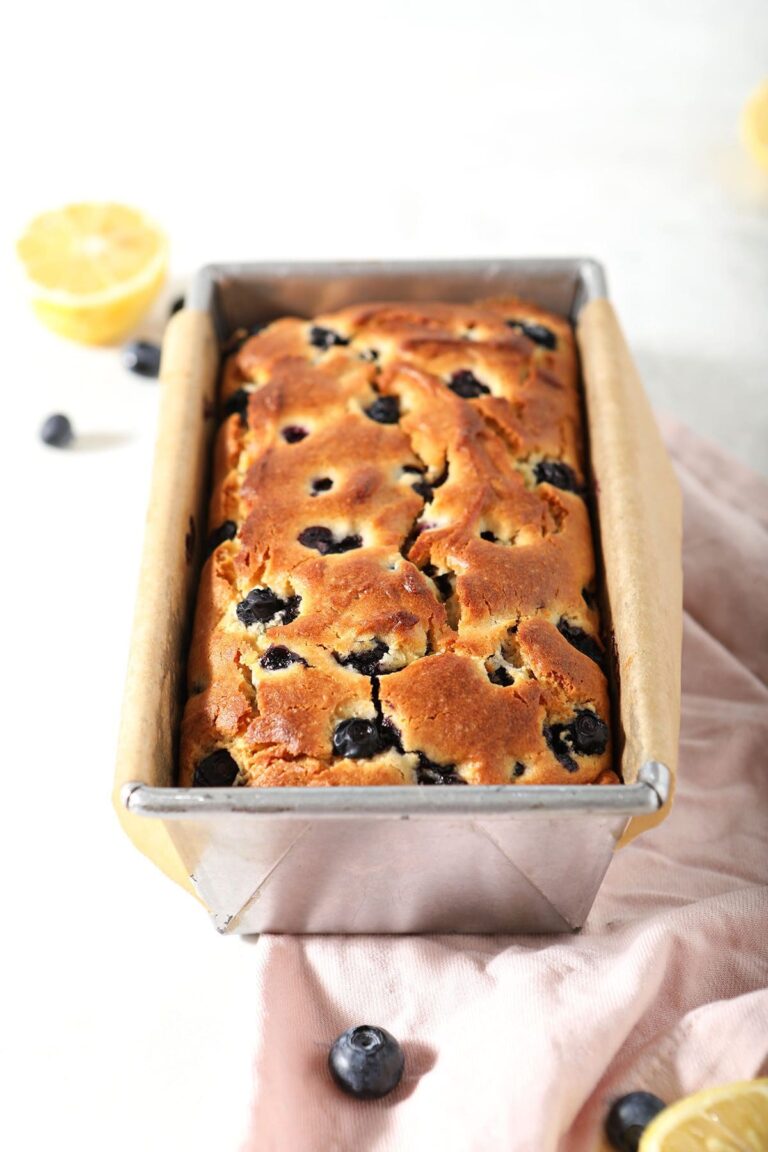 A loaf of Lemon Blueberry Bread in a loaf pan on marble