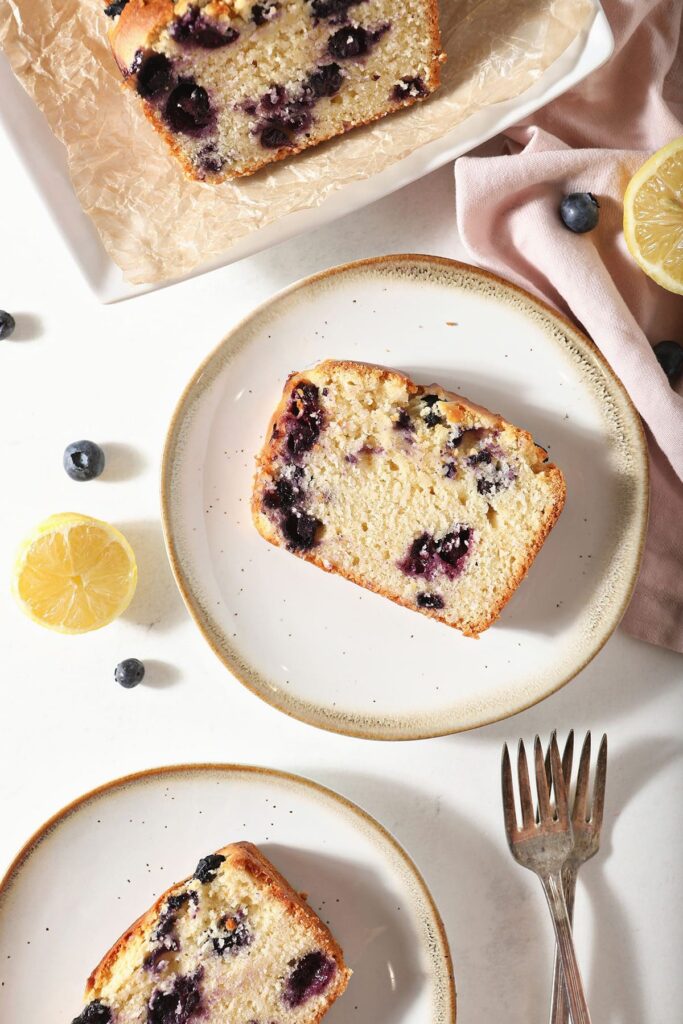 Slices of blueberry bread on plates with forks