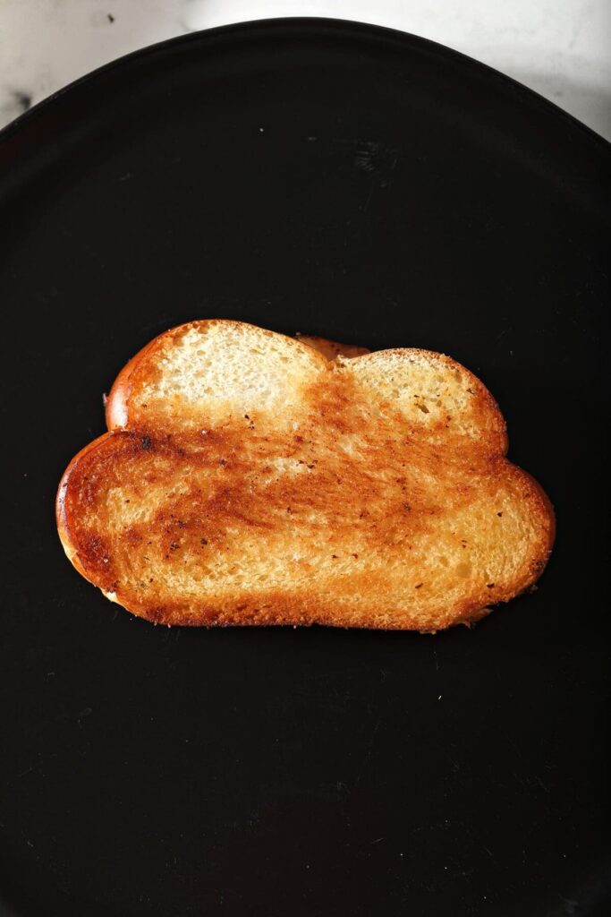 A golden brown piece of toast on a black plate