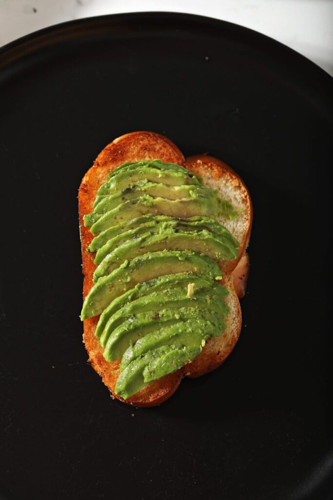 Sliced avocado on toast on a black plate