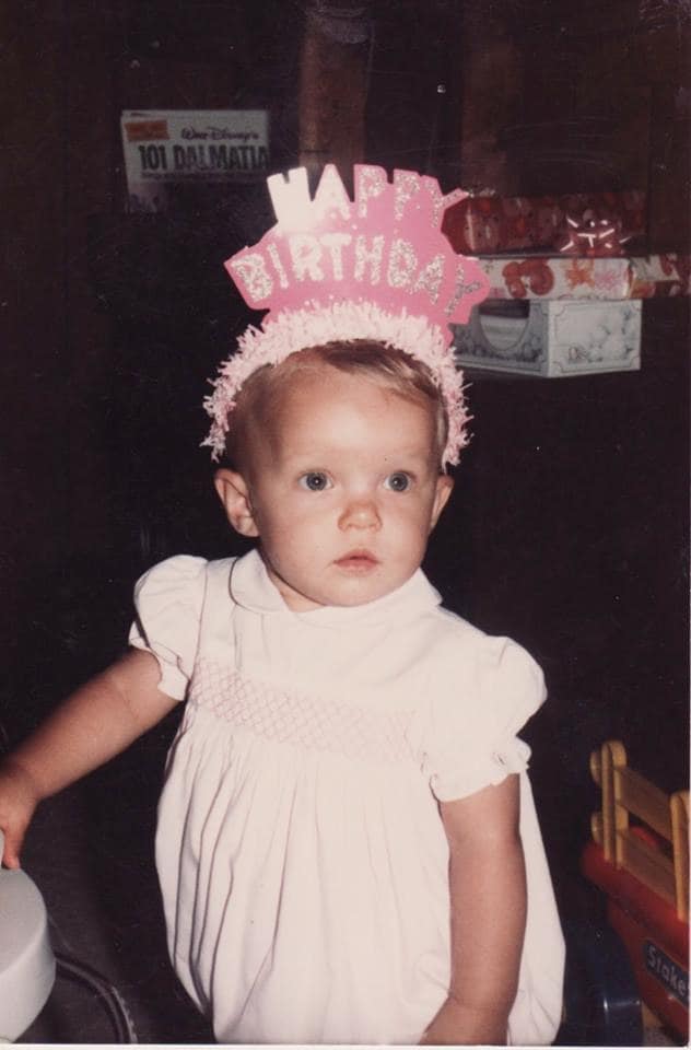 A little girl posing for a picture with happy birthday hat 