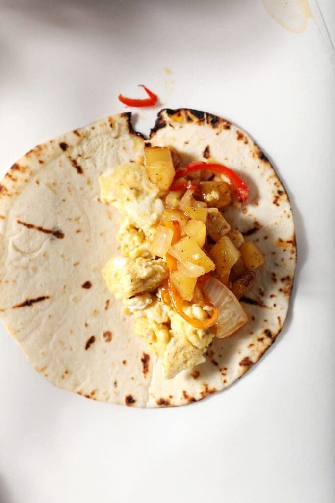 Scrambled eggs and potatoes on a tortilla on a sheet of parchment