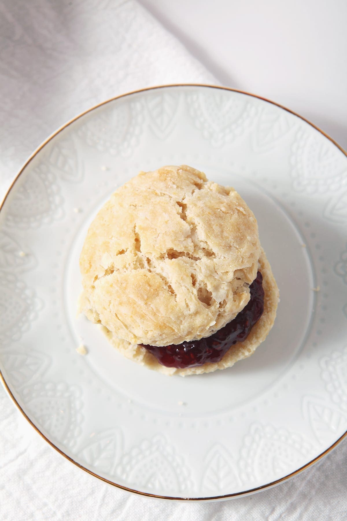 A vegan biscuit with jam on a white plate, from above