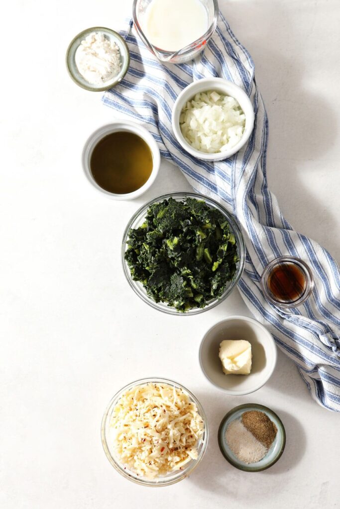 Ingredients to make creamy kale Madeline in bowls on marble with a blue striped towel