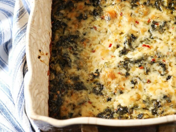 A casserole dish of kale Madeline with a blue striped towel