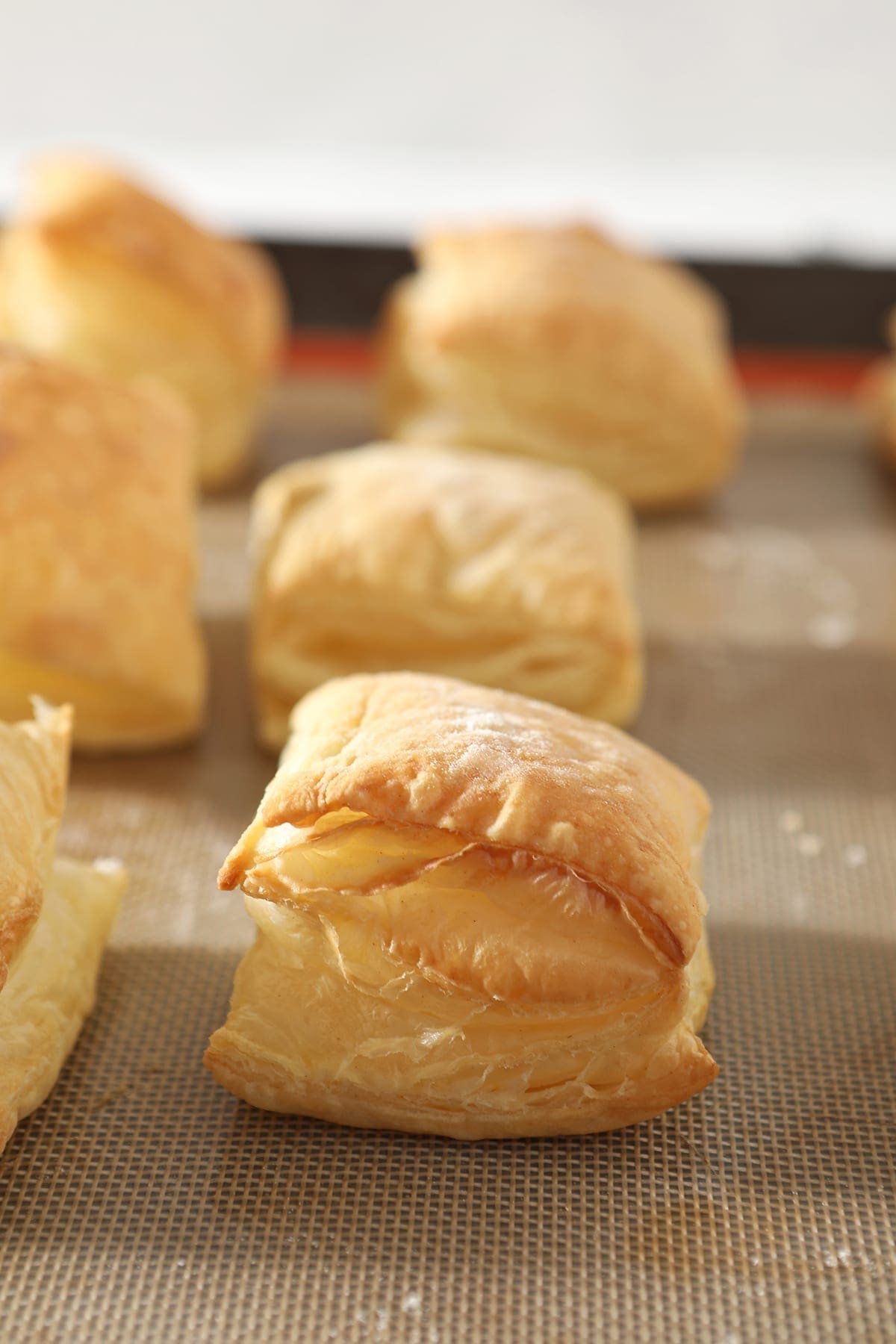 Baked squares of puff pastry on a Silpat-lined baking sheet