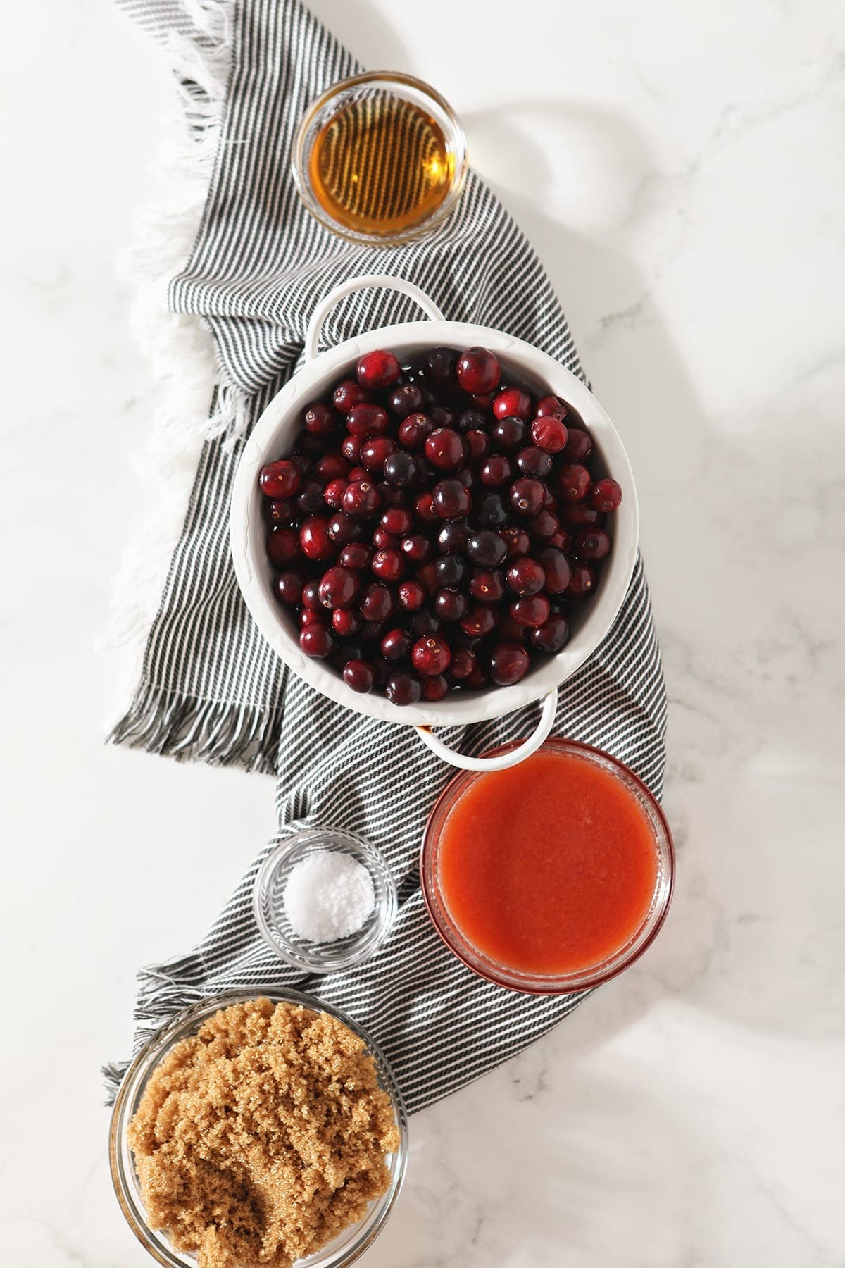 Fresh cranberries, orange juice, brown sugar, salt, and rum on a gray striped towel