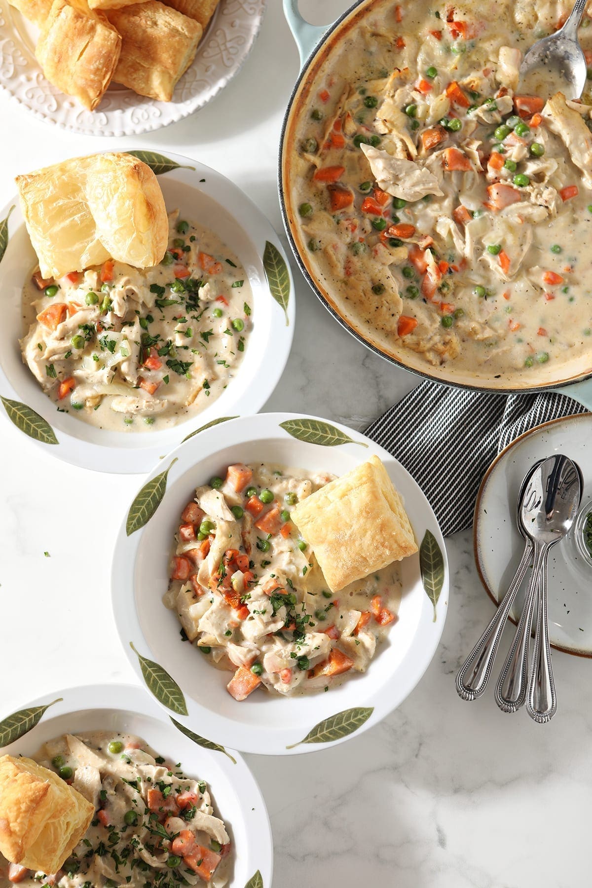 turkey pot pie in two white bowls with silver spoons