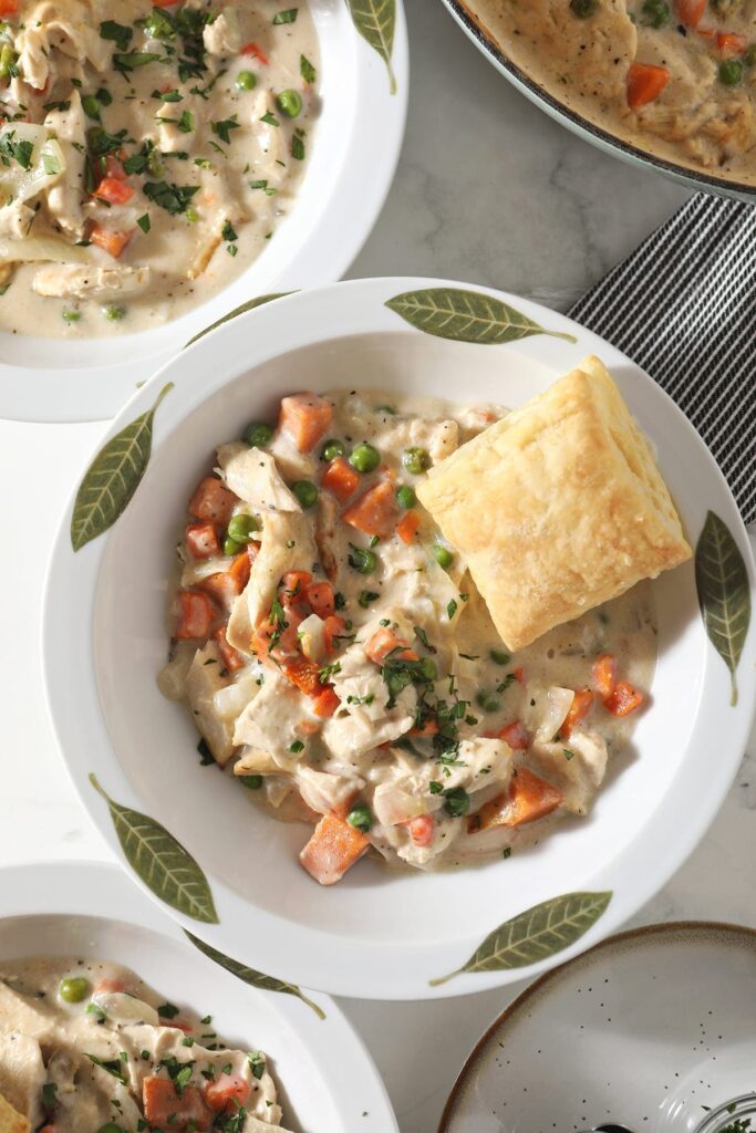 Close up of a decorative bowl holding a serving of Turkey Pot Pie topped with a golden puff pastry square