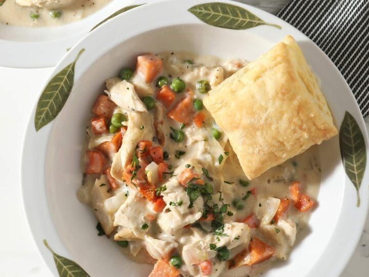 Close up of a decorative bowl holding a serving of Turkey Pot Pie topped with a golden puff pastry square