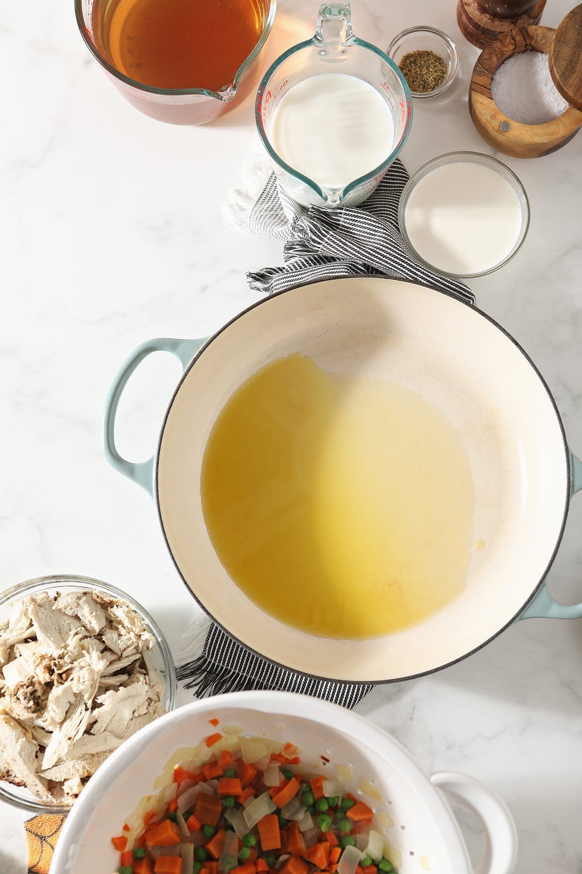 Melted butter in a Dutch oven is surrounded by other ingredients