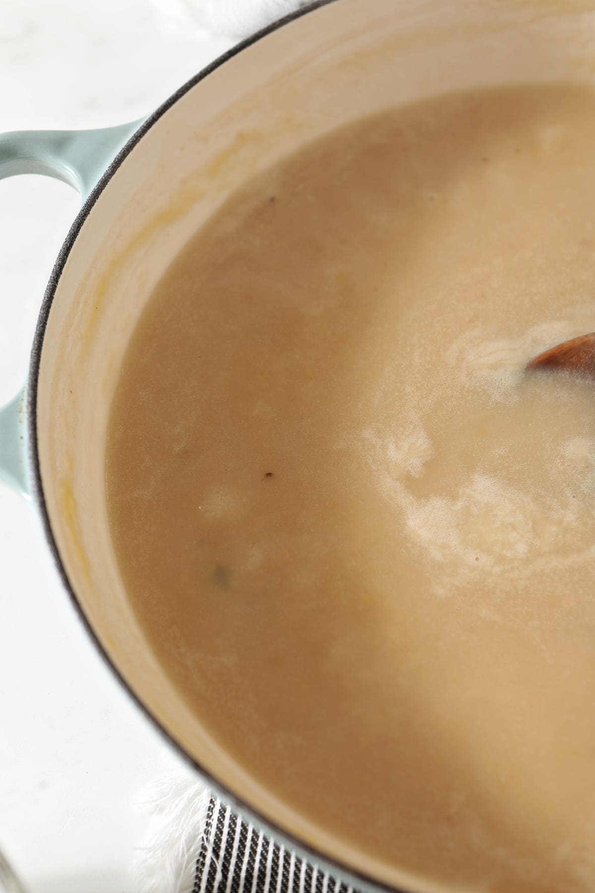 Close up of the vegetable stock being stirred into the roux