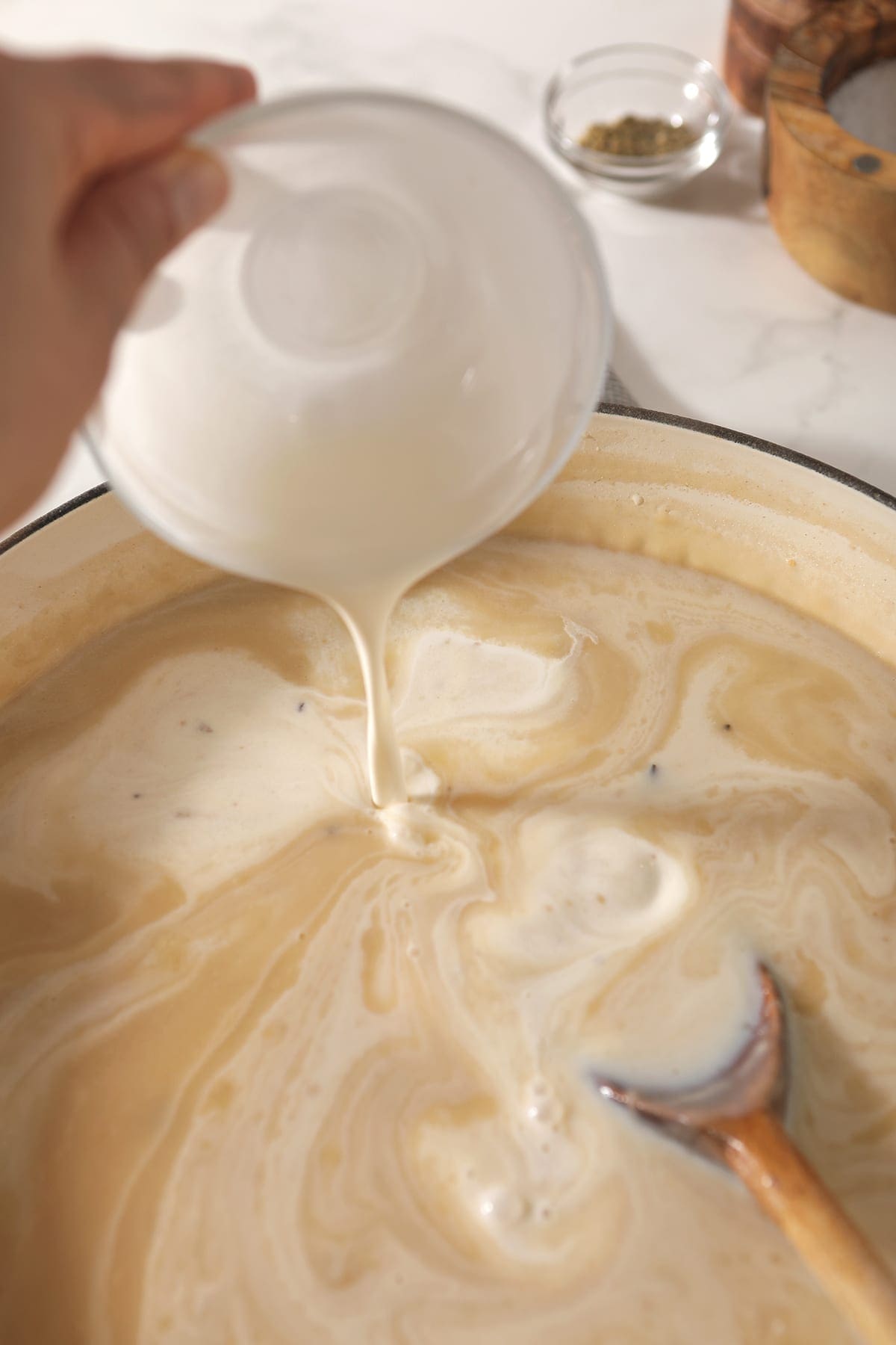 Cream pours into a Dutch oven holding a golden-colored mixture