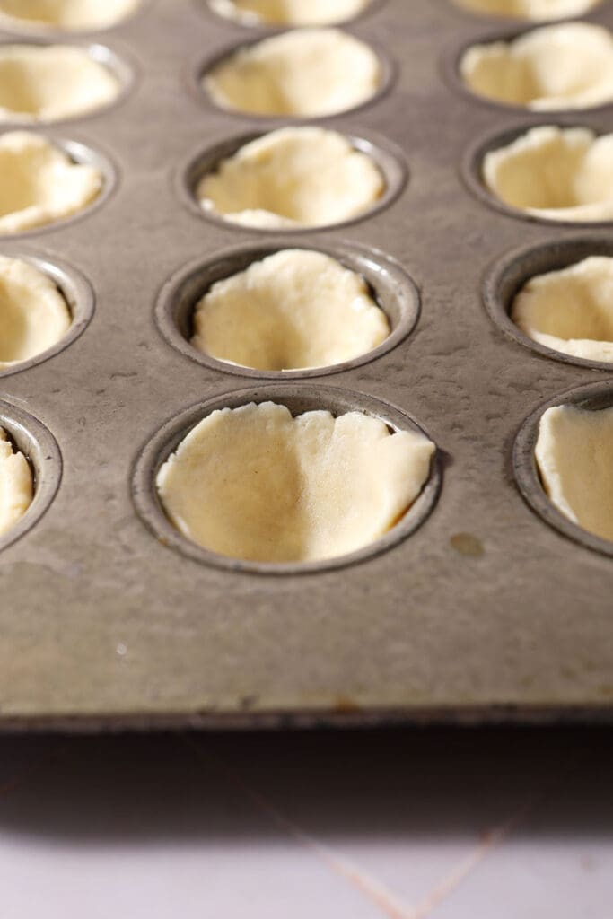 mini pie crusts in a mini muffin tin before baking