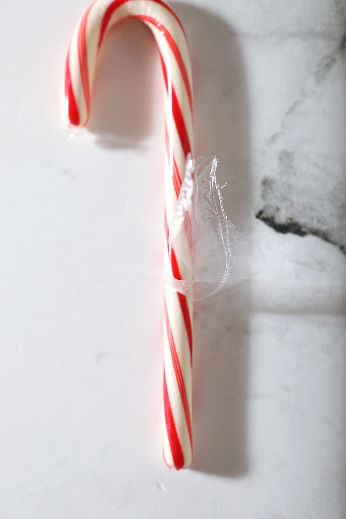 Close up of a half-peeled candy cane on marble