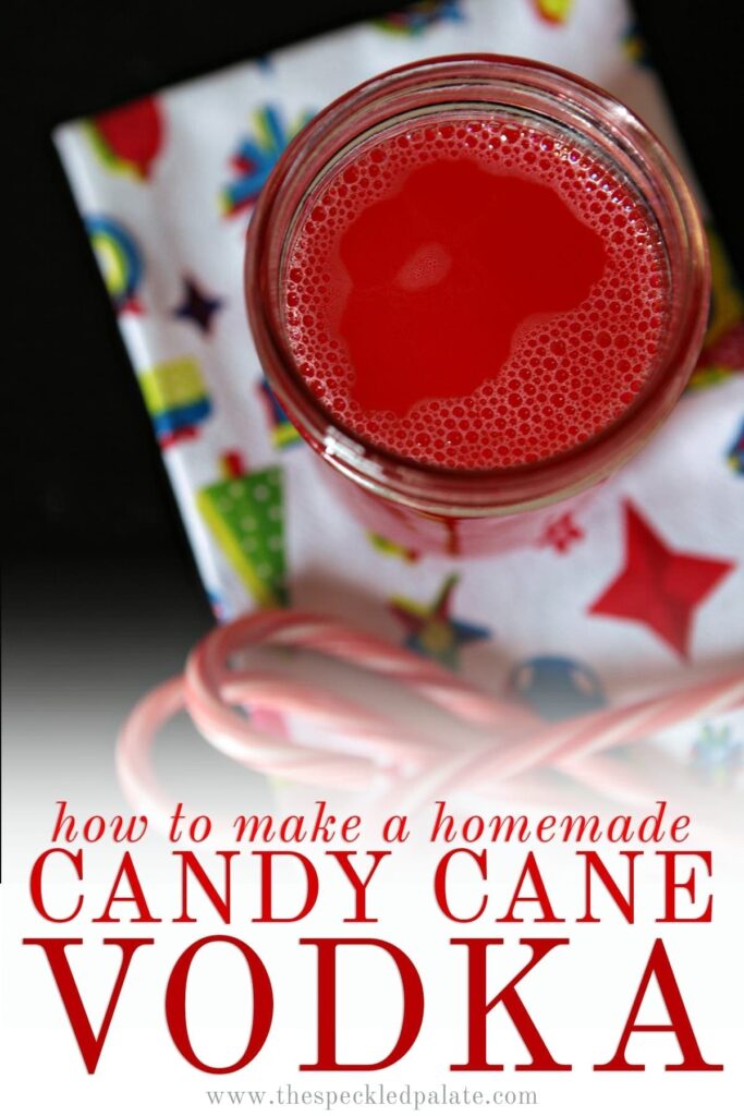 Close up of a mason jar of peppermint vodka next to candy canes on a Christmas-patterned white towel with the text 'how to make a homemade candy cane vodka'