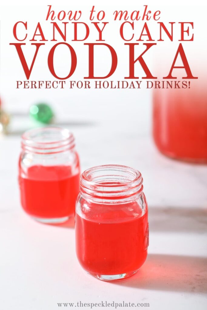 Two shot glasses of peppermint vodka on a marble surface next to a mason jar full of the candy cane-infused vodka with the text 'how to make candy cane vodka. perfect for holiday drinks!'