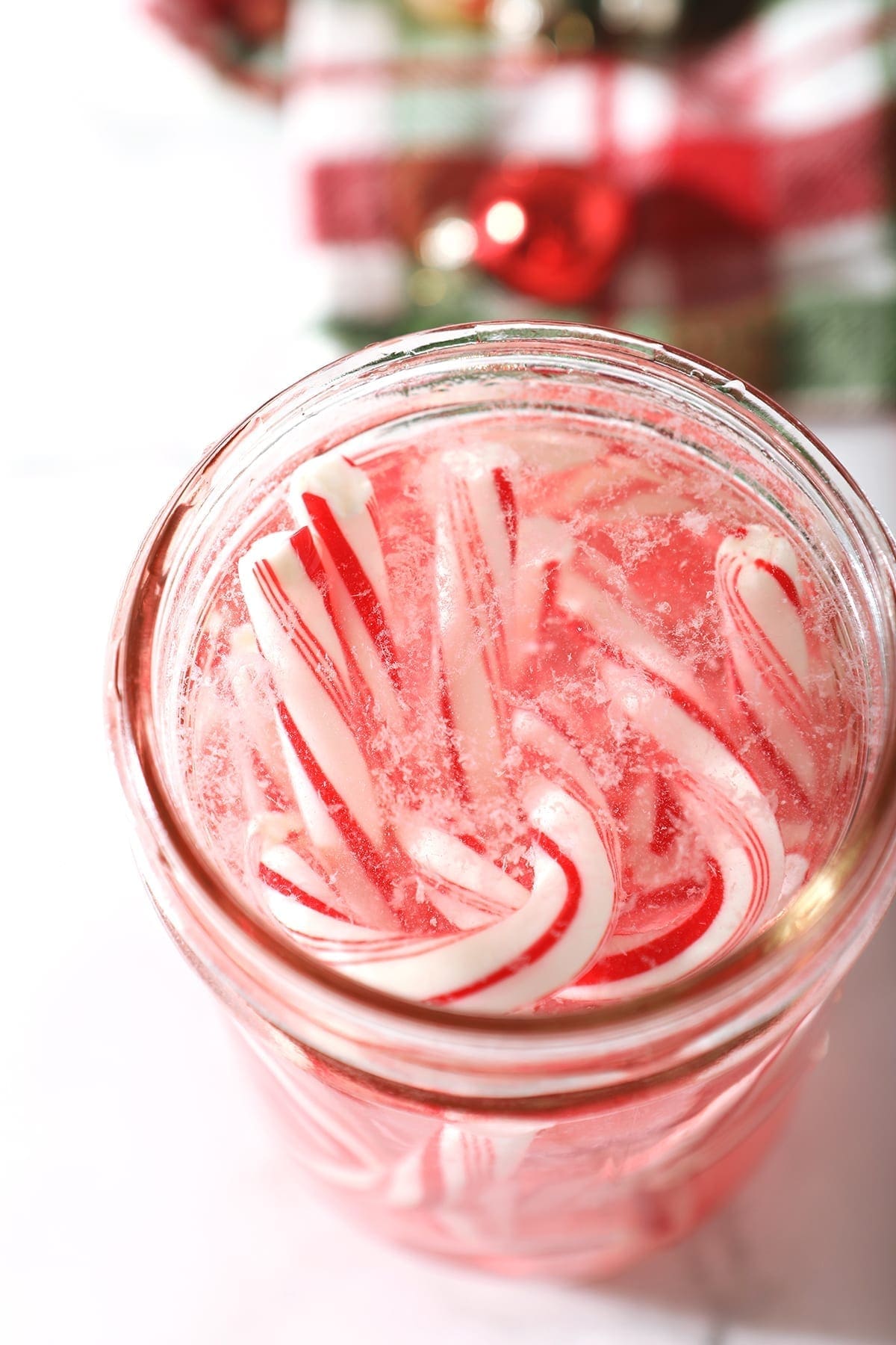 Close up of candy canes dissolving into a mason jar of vodka