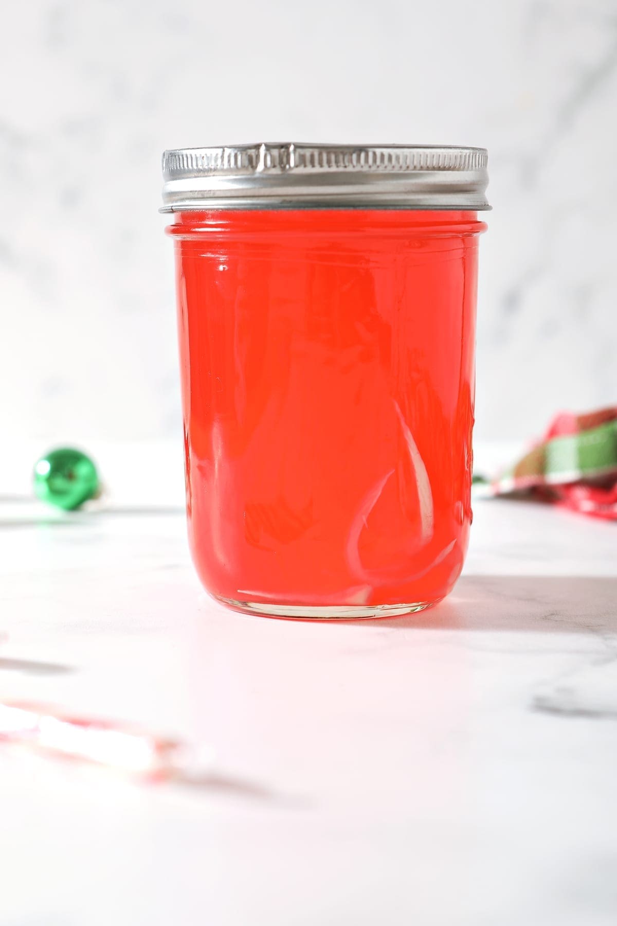 A bright red liquid is left in a mason jar after candy canes dissolve into vodka