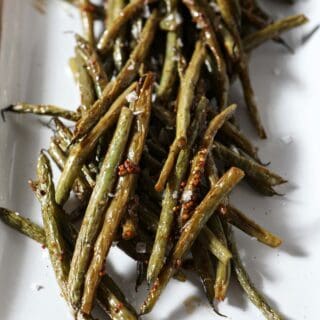 Roasted green beans on a white platter