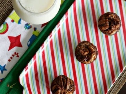 Overhead view of bourbon pecan tassies on holiday plate with glass of milk