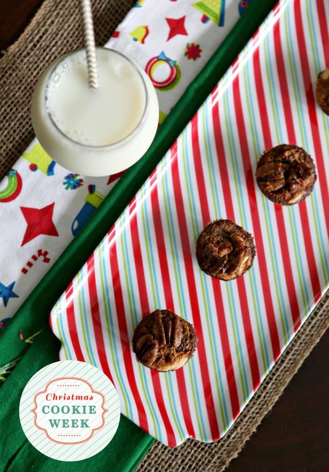 Overhead view of bourbon pecan tassies on striped holiday plate with glass of milk