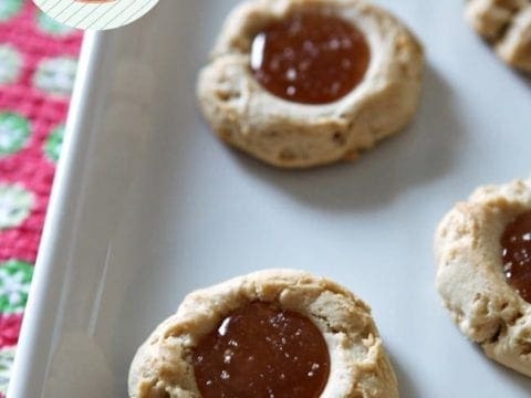 Close up of thumbprint cookies on a white tray with caramel