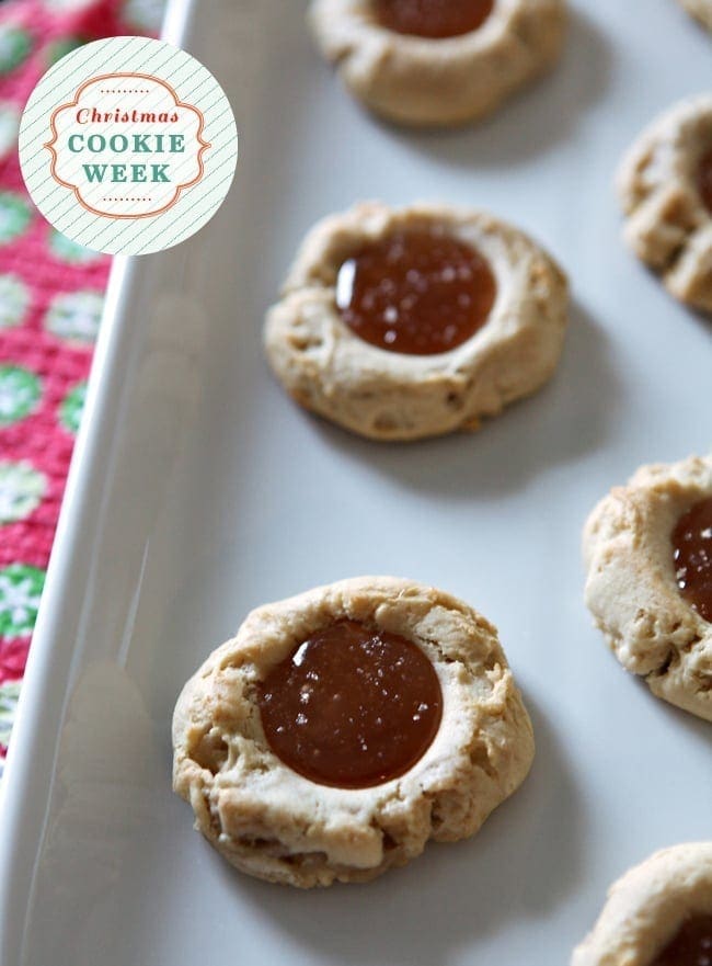 Close up of thumbprint cookies on a white tray with caramel