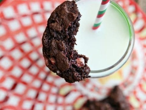 A half-eaten cookie sits on top of a glass of milk